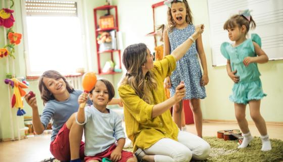 Children playing with their teacher on a mat 