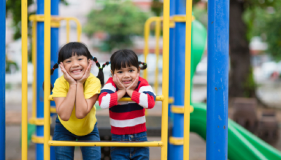 Two children smiling on a playground