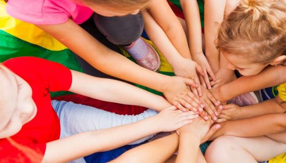 A group of children putting their hands in the middle of a circle