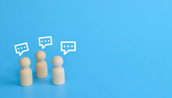 An image showing wooden people figures with speech bubbles above them and a blue background