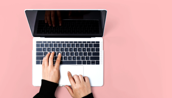 An image showing a birds eye view of a laptop with a pink background
