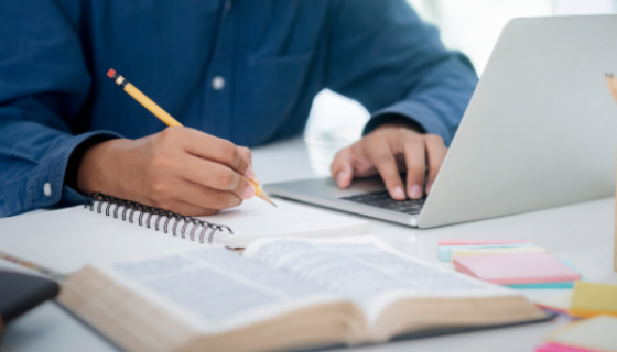An image showing a person studying with a laptop, books and notepad