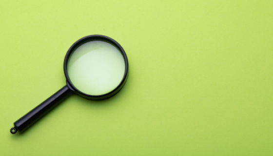 An image with a lime green background showing a black magnifying glass 