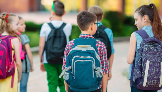 An image of children with backpacks on walking in the opposite direction