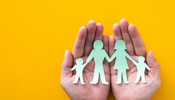 An image showing a cut out of people in hands with a yellow background