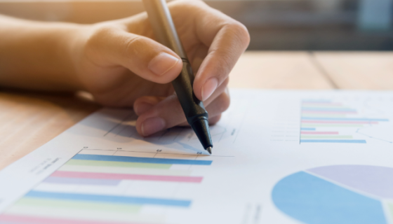 An image of a person's hand holding a pen and marking a report. 