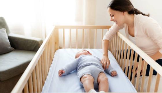 Baby Sleeping On Back In Cot With Educator Watching