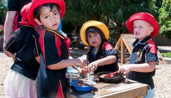 Kindergarten children playing with a mud kitchen