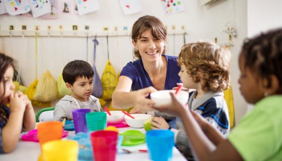 Four children with female teacher doing craft