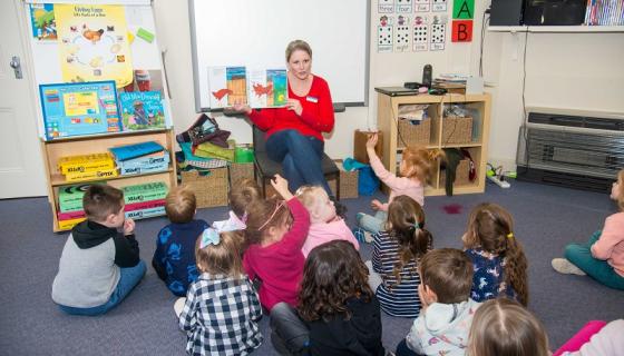 Rachel Douglas, director of Chandler's Hill Kindergarten reads to children on mat